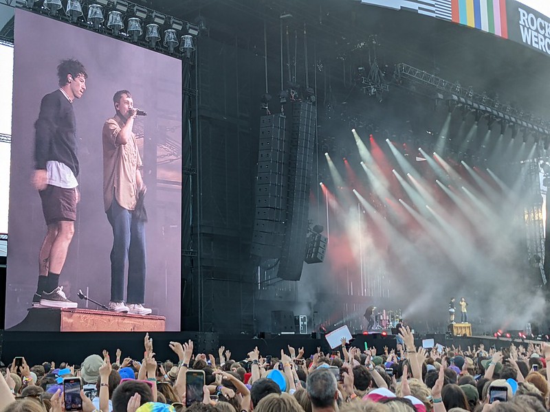 Twenty One Pilots performing on the Main stage, standing on the piano.