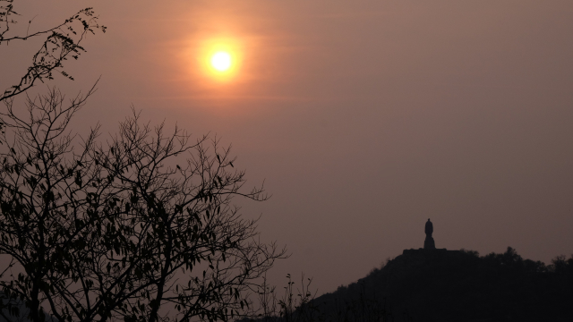 Large monument of a soldier with sun setting in the misty background