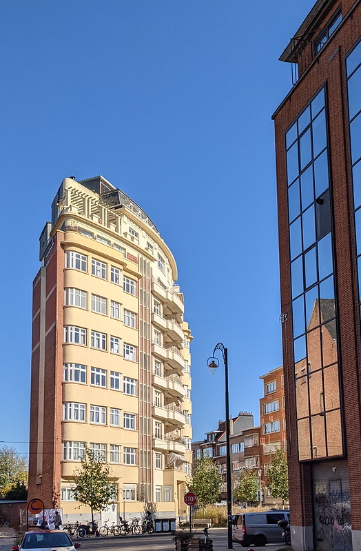 Wedge shaped apartment block next to reflections in glass building