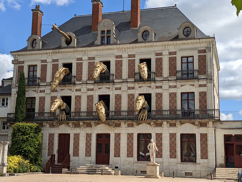 Six dragon heads reaching out of the large windows of the House of Magic in Blois