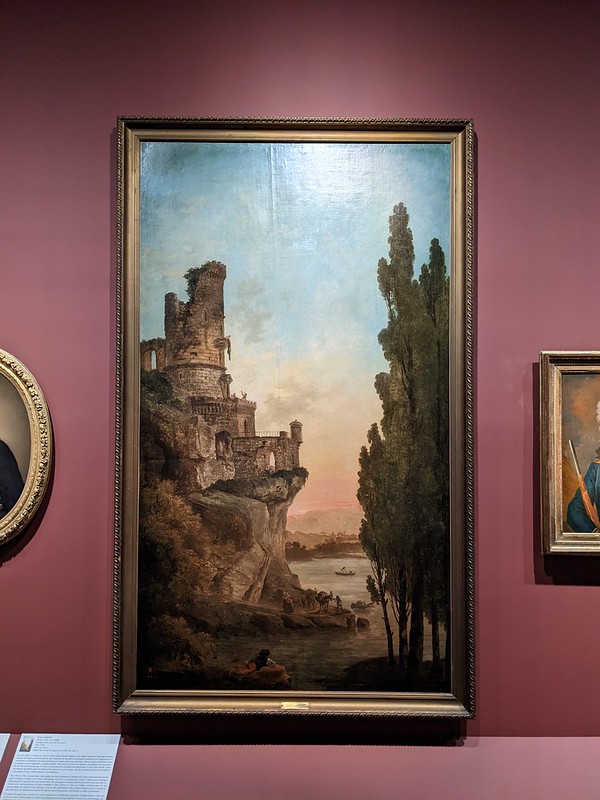 Painting of castle ruins on a hill to the left, with tall tress to right and a boat on a lake in the background with the sunsetting in the distance.
