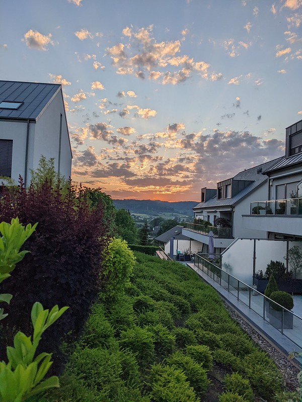 A lovely sunset in the distance, with red and orange clouds framed by buildings to either side.