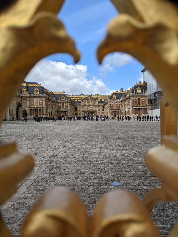 View of the Versailles castle through a hear shape in the gate made by two golden eagles 