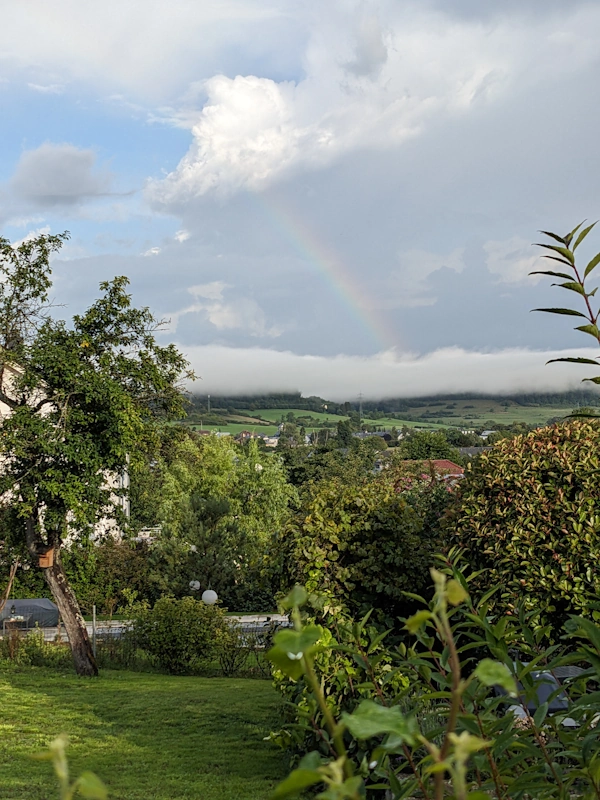 Rainbow over a valley, in front and through the clouds