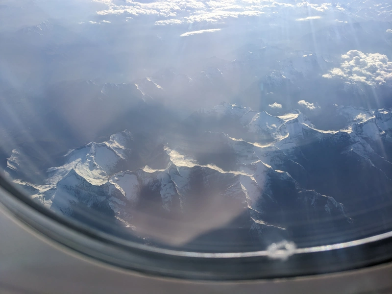 View of the snow capped Alps through the airplane window