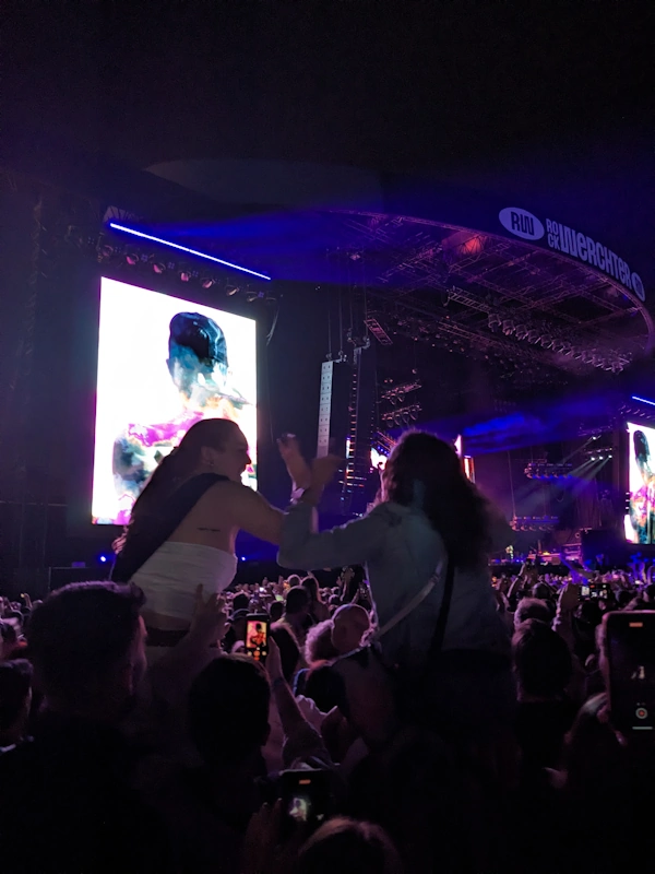 Two girls on the shoulders of their friends in front of the main stage watching Red Hot Chili Peppers.