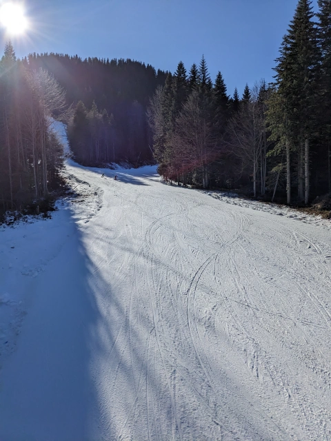 White ski piste cutting through the forest in the hills