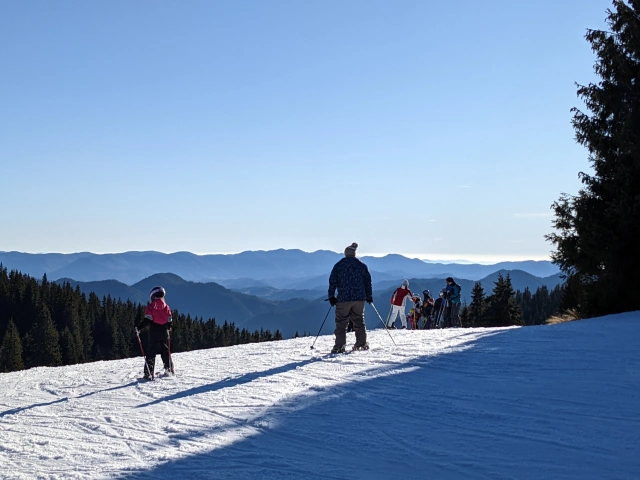 Looking on to the back of Skiers just before they go over the edge of the ski slope