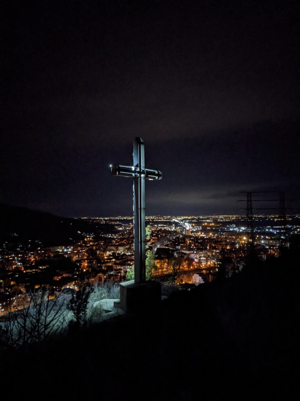 Cross lit up at night with Asenovgrad glowing in the background