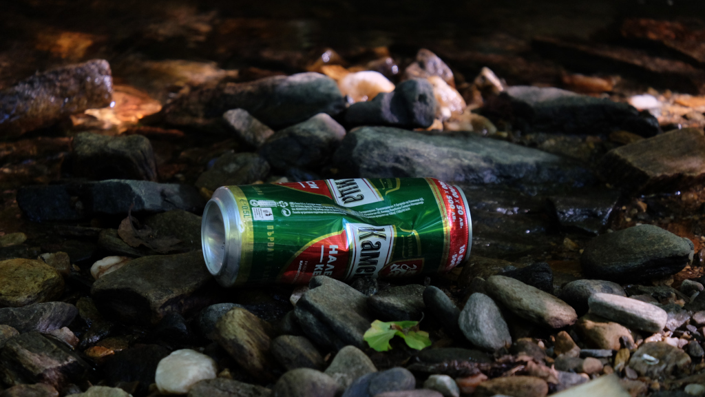 A can of beer lying in a stream in the setting sun.